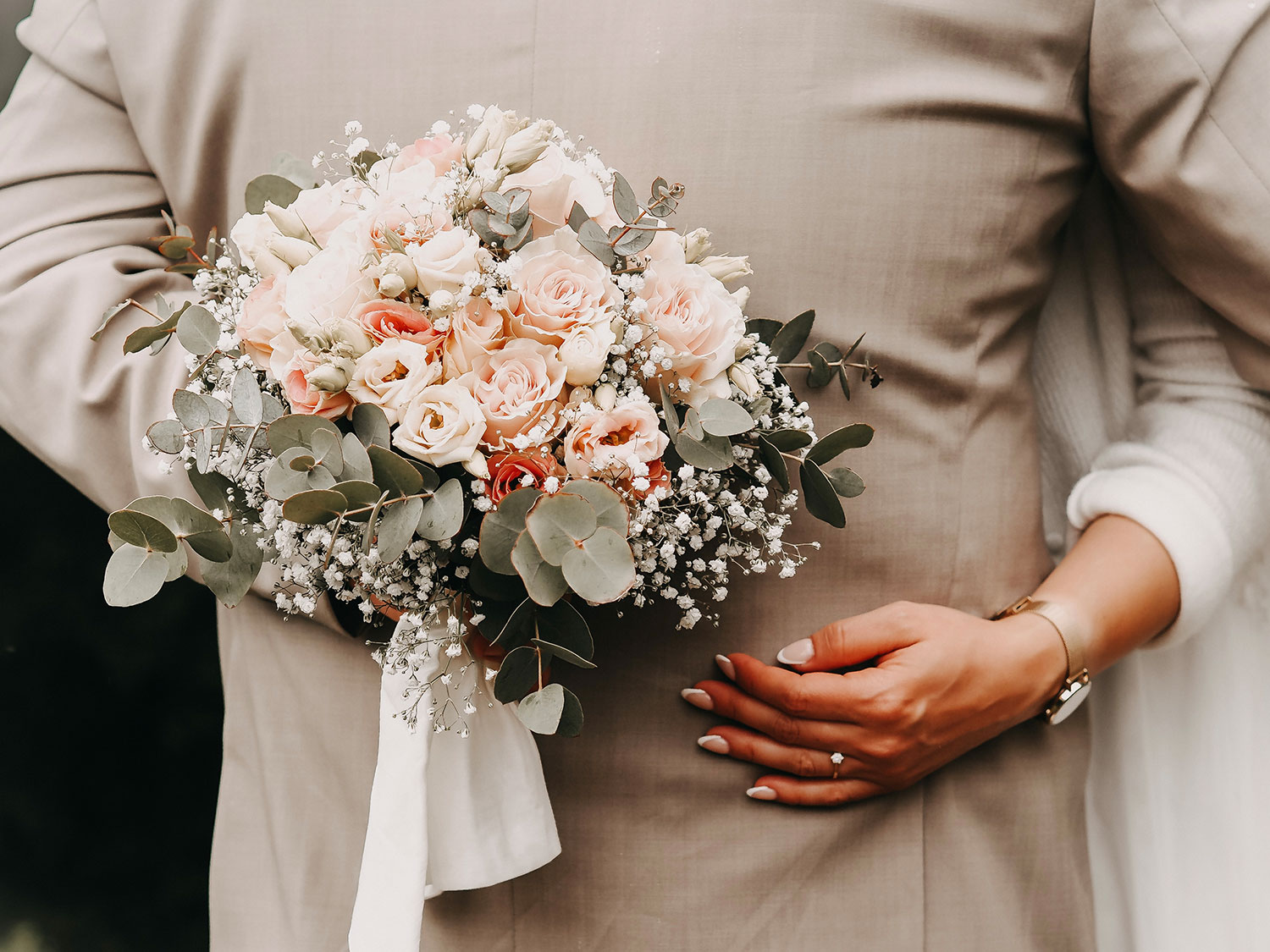 Brautpaar umarmt sich und die Braut hält einen Brautstrauss